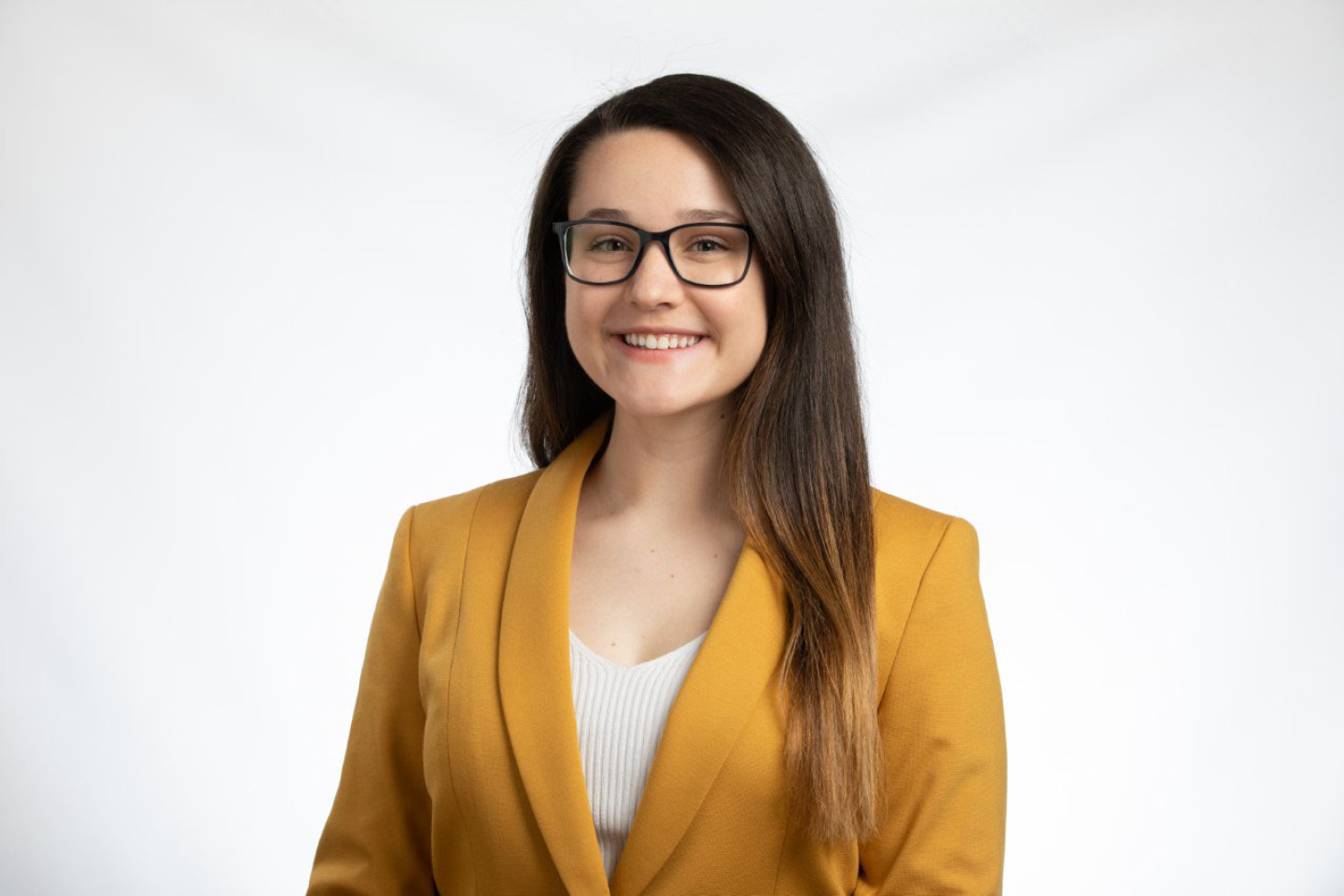 Professional photo of Nicole Miller wearing a yellow blazer against a white background