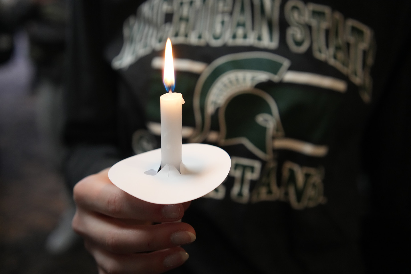 A close-up view of a hand holding a white candle.