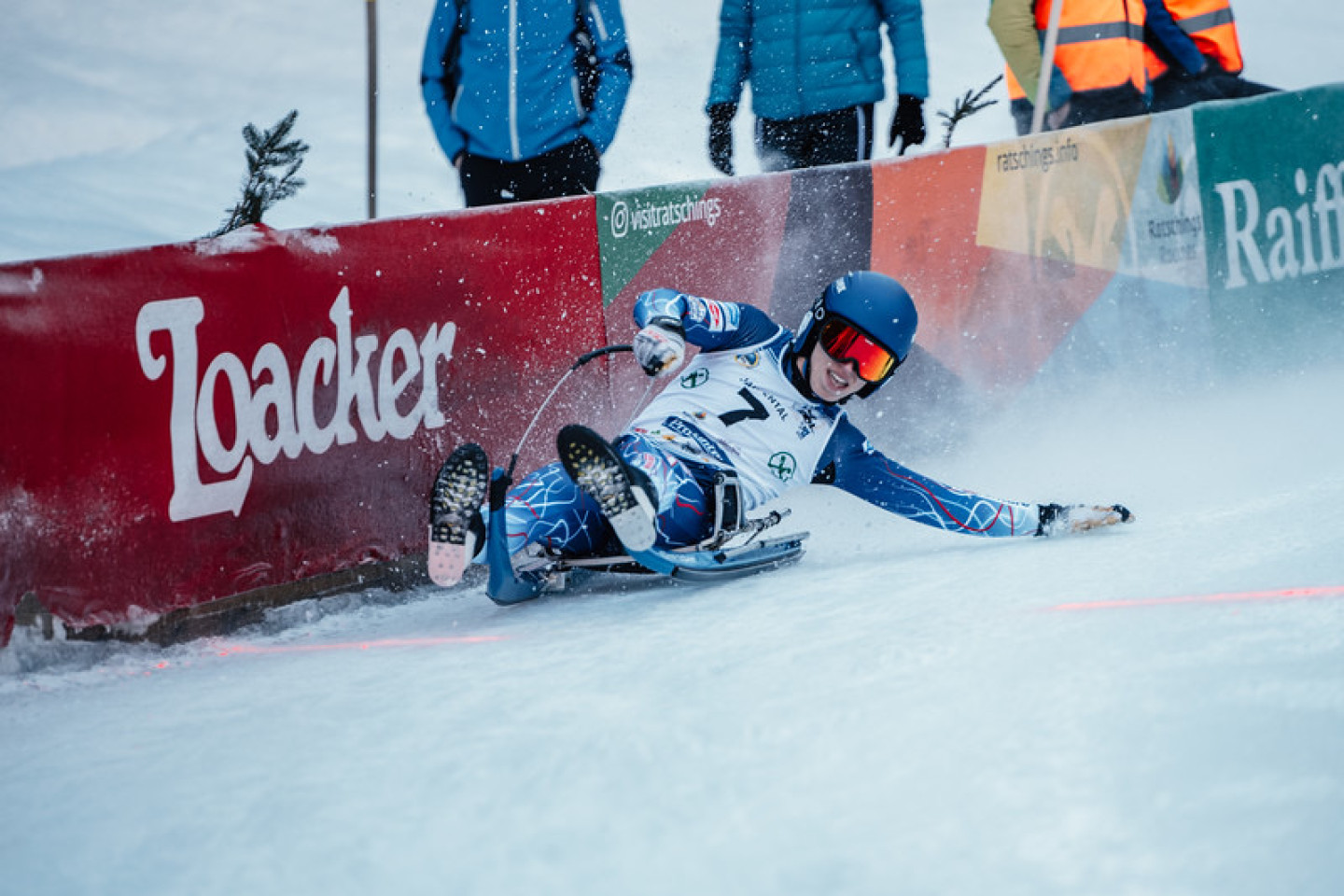 A luge athlete leans to the side to steer his sled down the track.
