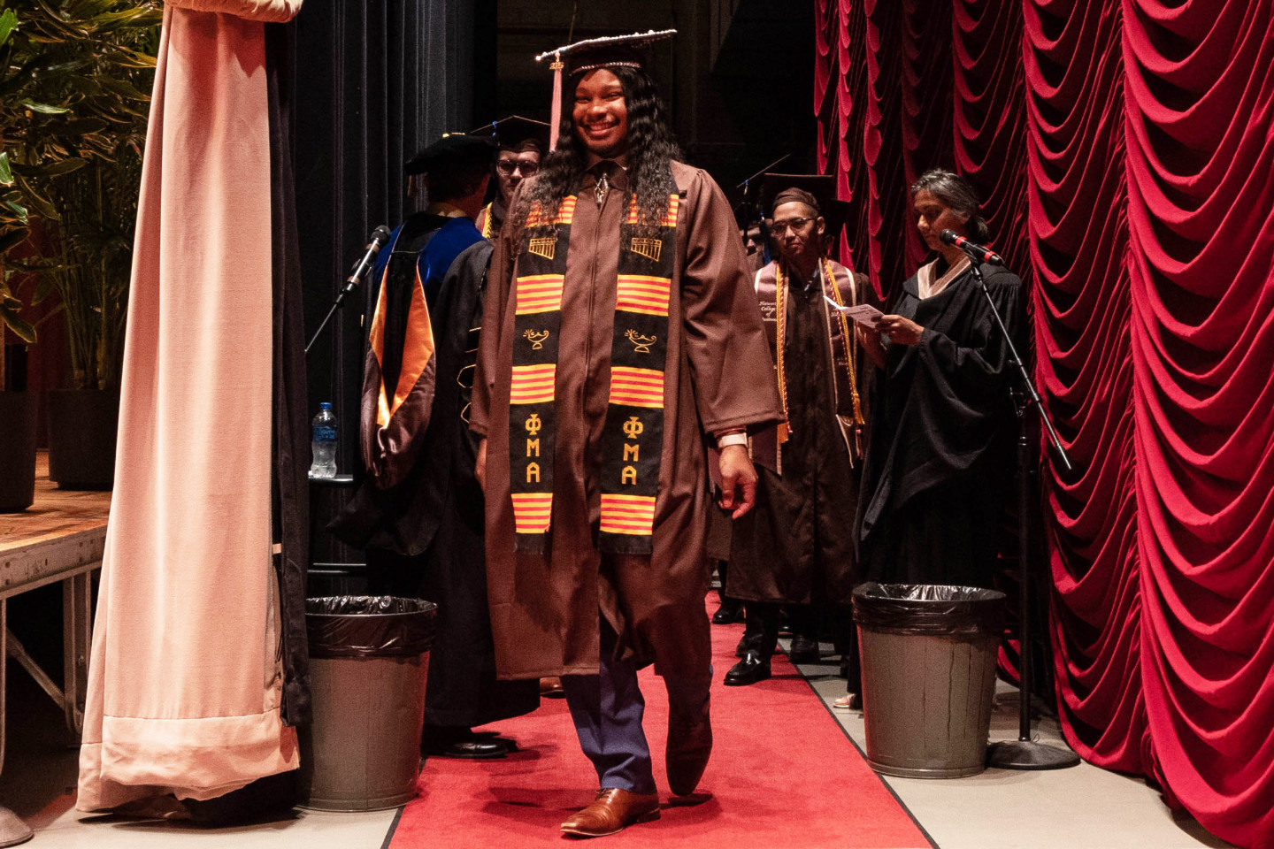 Marcell Pierre Whitfield walks across the red carpet backstage at commencement.
