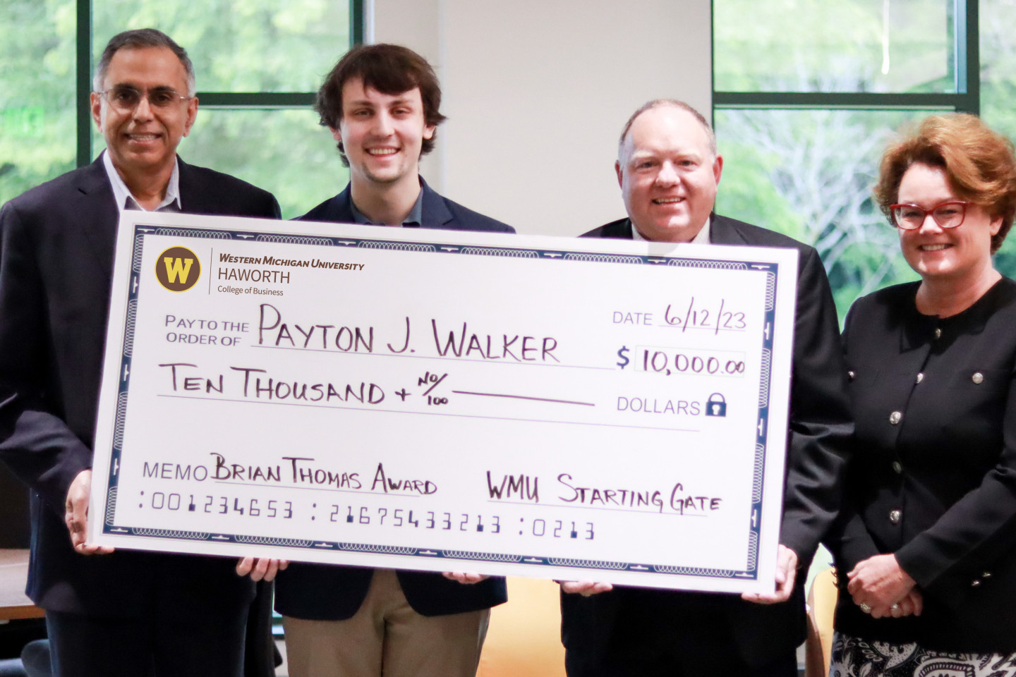 Payton Walker accepts $10,000 award with Dean Satish Deshpande, Dr. Decker Hains, chair of the Department of Management, and Tamara Davis, director of Staring Gate