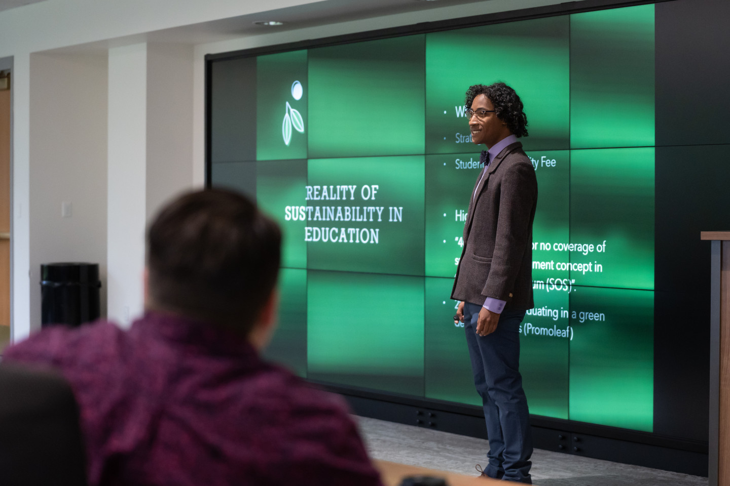 Keeton Bigham-Tsai stands in front of a green presentation screen.