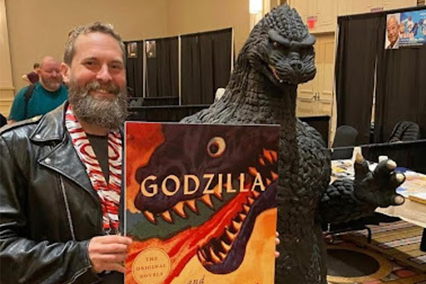 Jeffrey Angles stands next to a statue of Godzilla.
