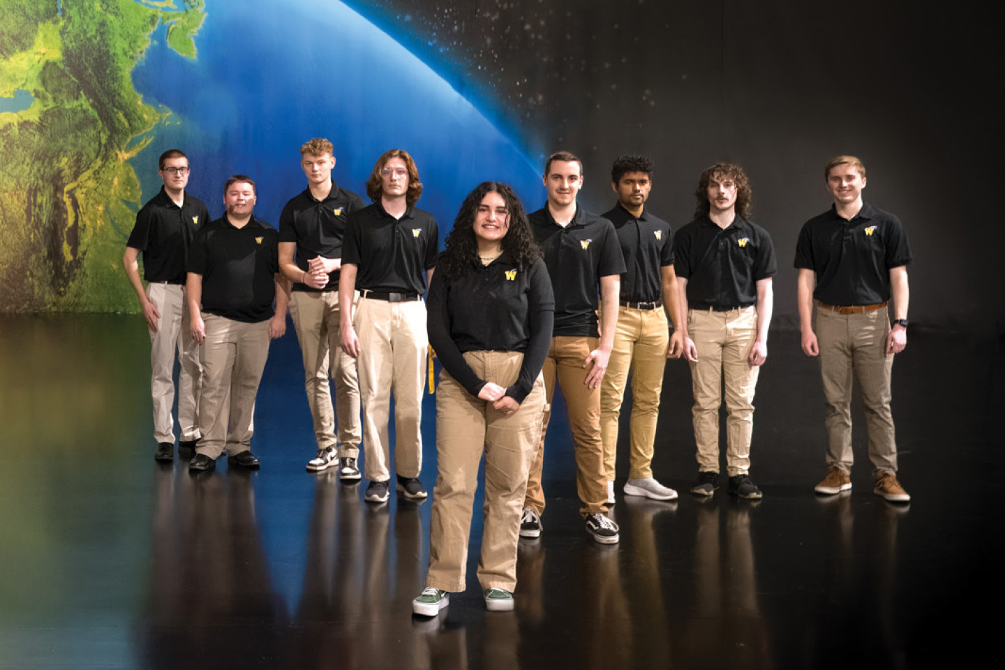 A group photo of WALI students in front of a mural of the Earth.