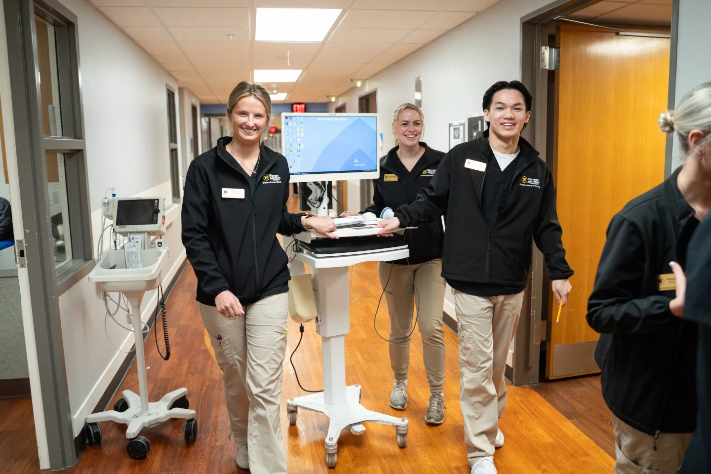 Three WMU students push a cart down the hall of a hospital.