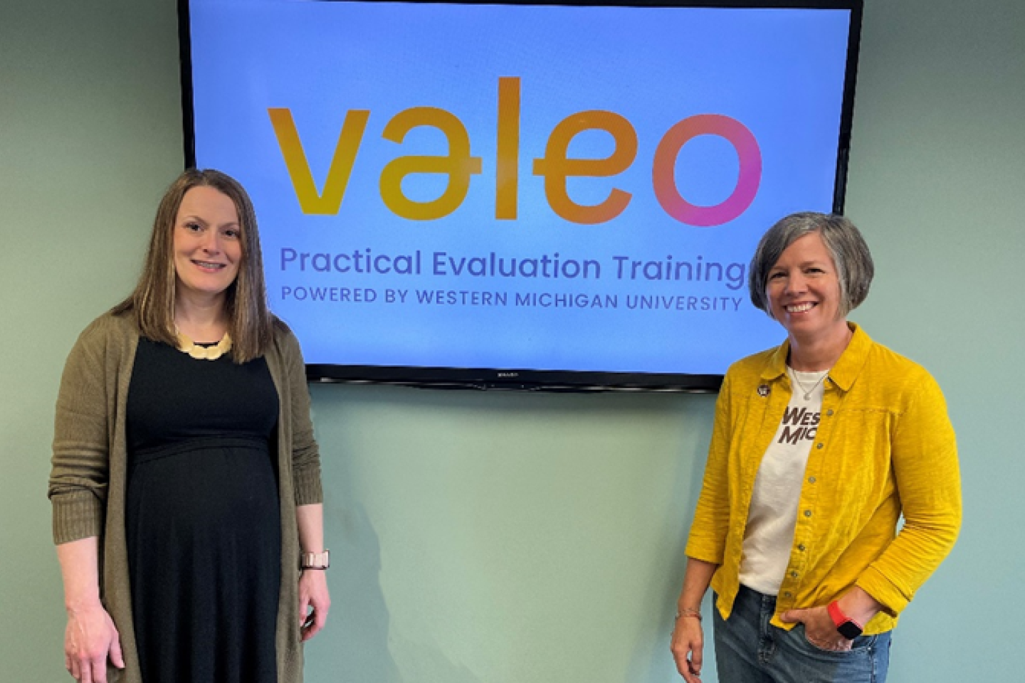 Kelly Robertson and Lori Wingate stand next to a sign that says "Valeo."