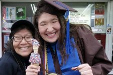 mother and daughter in graduation cap and gown holding ice cream