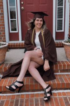 Elma Celebic sitting on steps wearing graduation cap and gown