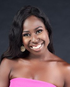 Psyche Terry in front of a grey background wearing a blue dress and smiling