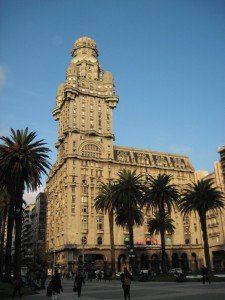 tall building in south america with palm trees in front of it and a blue sky behind