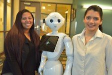 Two students stand next to life-size robot.