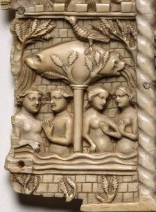 A fourteenth-century carved ivory panel depicting two couples under a tree in a walled garden.