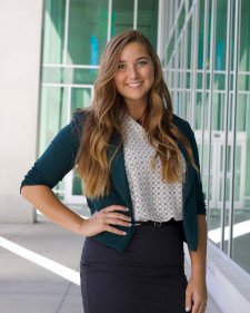 Miranda McNiven stands outside Sangren Hall wearing a green sweater and black skirt