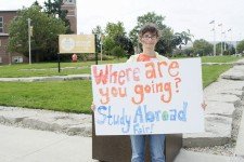 Photo of a student holding a sign which reads, Where are you going? Study Abroad Fair!