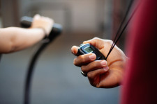 Photo of a person's hand on an exercise bike and another hand holding a stopwatch