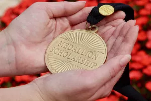 Hands holding a Medallion against a red background