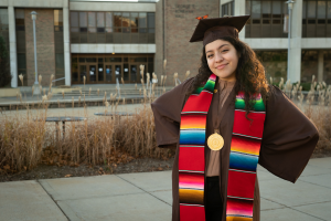 A student wearing brown graduation cape and gown.