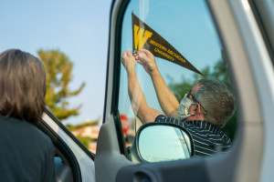 A person puts a Western Michigan University pennant on his car antenna.