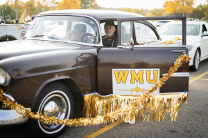 A person sits in a vintage car decorated with gold garland.