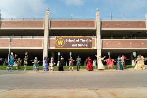 WMU Theatre students stand in front of a School of Theatre and Dance banner.