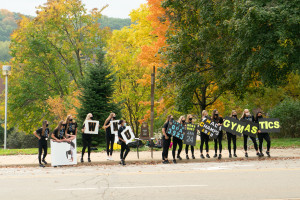 The WMU gymnastics team holds signs along the side of the road.