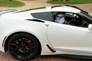 A Storm Trooper rides in the passenger seat of a car.