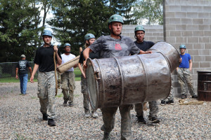 Campers carry large metal barrels.