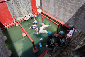 Campers climb across chains over water as they complete a scenario on the leadership reaction course.