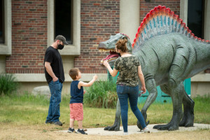 A family looks at the spinosaurus statue.