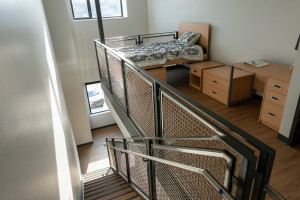 A bed in a loft area of an apartment.