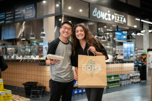 Dominic Gee and Korina Luco hold packages of food at Dom's Kitchen & Market