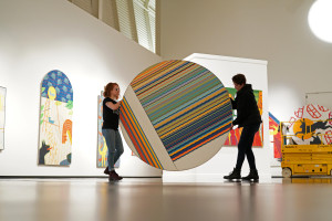 Students carry a large, circular painting.