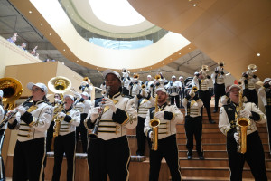 Marching band members play their instruments on stairs.