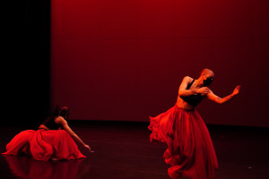 Dancers in red skirts dance on stage.