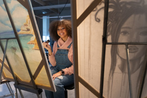 Sharmane Flanders smiles through the opening between two paint canvases.