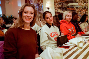 Three students sit together at a dinner table in a restaurant.