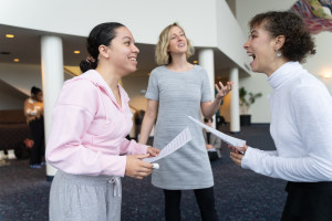 Two students look at each other while holding scripts.