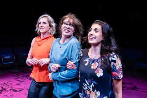 Three women walk arm-in-arm.