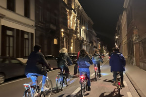 People ride bikes through a city street.