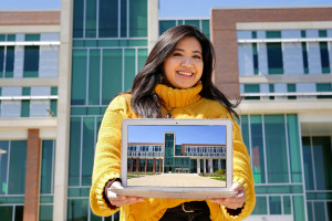 A student ambassador holds up a laptop displaying a photo of Sangren Hall.