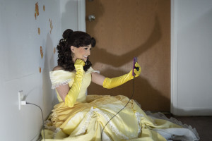 A student dressed as Belle from Beauty and the Beast smiles into her phone during a video call.