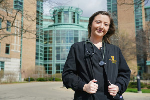 A nursing student wearing a stethoscope stands outside Bronson Hospital.