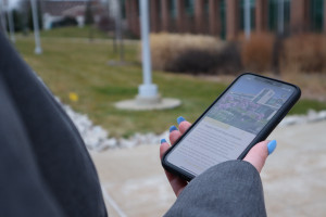 A woman holds a phone with the campus tour app open.