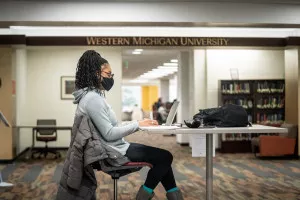 A student wearing a mask sitting in Waldo Library.