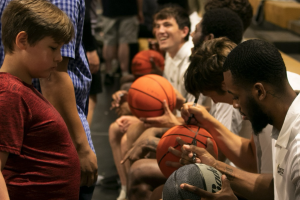 Players using markers to sign basketballs.