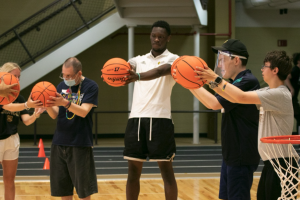 A WMU Basketball player teaches students how to pass the basketball.