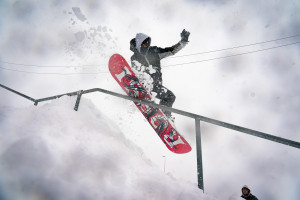 A snowboarder going down a railing in the snow.