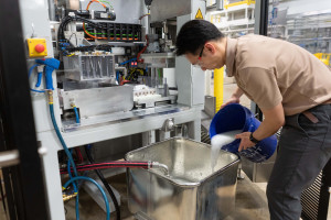 Jason Wang pours a wet slurry into a Pilot Plant machine.