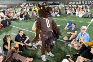 Buster Bronco stands infront of a circle of students on the field of Waldo Stadium.