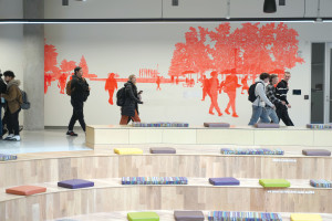 Students walking in front of a mural in student center